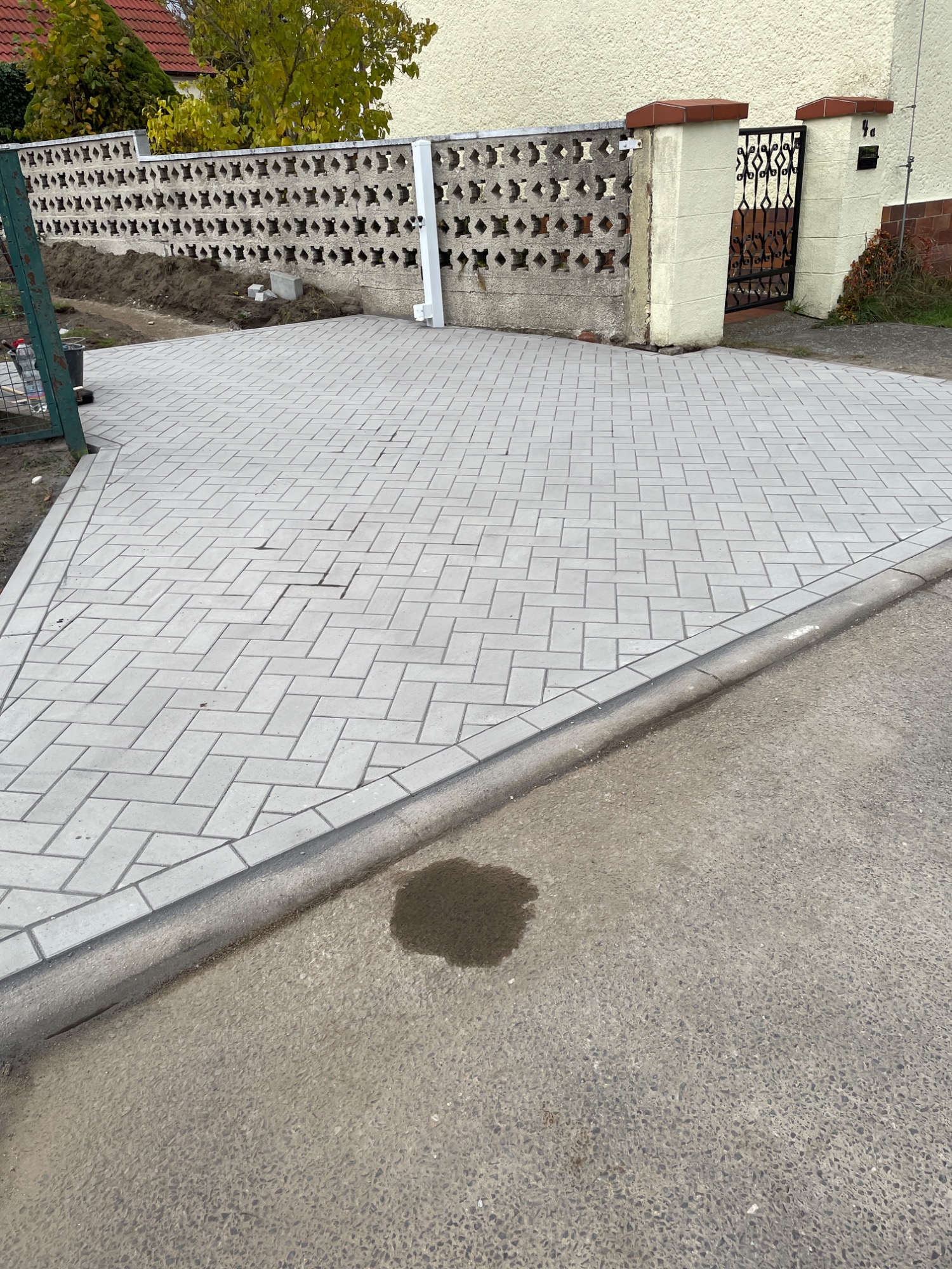 Pflasterweg mit schräger Auffahrt und einem kleinen dunklen Fleck auf dem Boden.